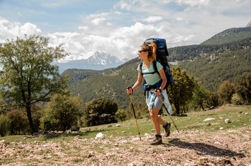 Female backpacker travelling down the road in hills