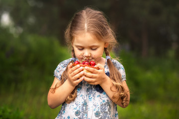 little girl holding a basket of cherries on nature in summer