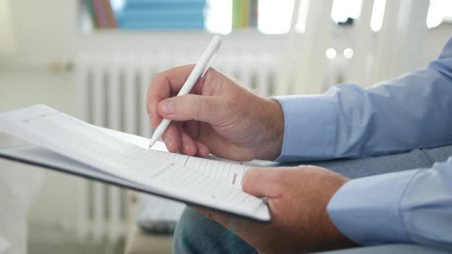 Businessman Image Sitting on a Chair in Office and Writing Information in Agenda