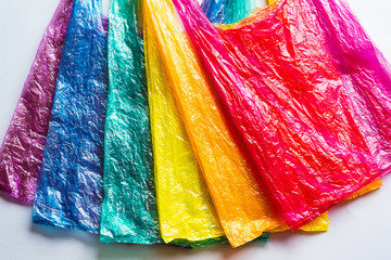 Several different colored plastic bags used on the gray surface are laid out in rainbow colors, a modern environmental concept.