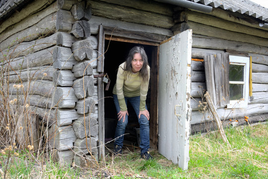 Young Pretty Woman Exiting Low Old Rural House Declined