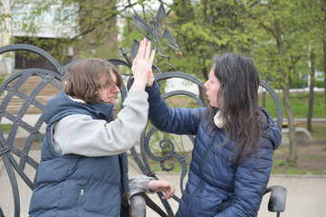 young mother and teenage son having fun playing in a city park on a sunny spring day