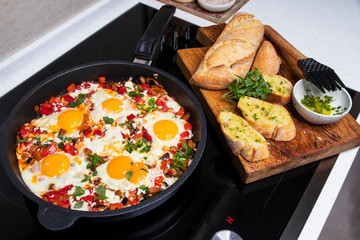 Fried eggs with vegetables and baguette spread with garlic sauce. Morning breakfast