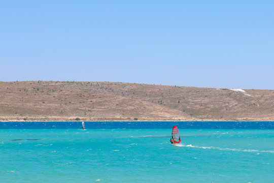 Windsurfer sails on turquoise waters of Alacati Windsurf Bay of Cesme, Turkey.