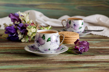 A cup with morning coffee and a bouquet of wildflowers