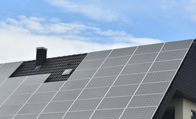 Solar panels installed on the roof of a house with tiles in Europe against the background of a blue sky. Green technology