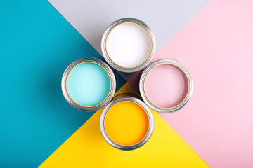 Four open cans of paint on bright symmetry background. Yellow, white, pink, turquoise colors of...
