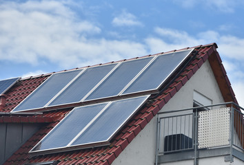 Solar panels installed on the roof of a house with tiles in Europe against the background of a blue sky. Green technology
