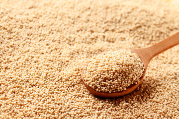 Wooden spoon with amaranth seeds on a amaranth background