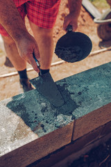 Bricklayer installing bricks on construction site..