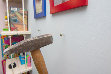 A hammer hammers a nail into the wall, hanging frames with photos