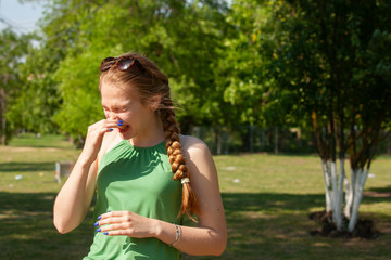 Fototapeta premium Young woman with allergy during sunny day is wiping her nose.