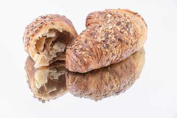 Tasty croissant and medium with sesame seeds on a mirror