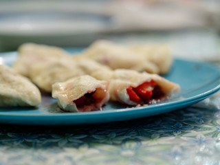 Delicious food dumplings with strawberries. Delicious hot dish of dough and berries. Home-made dish national Russian and Ukrainian cuisine. Close-up photo.