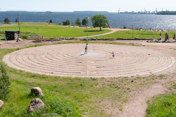 Circular labyrinth in the park. City of Kotka, Finland. People relax in the park and walk through the maze.