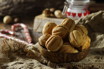 Close-up of nuts from dough, lying in a coconut bowl on a sack napkin in combination with blurred objects in the background.