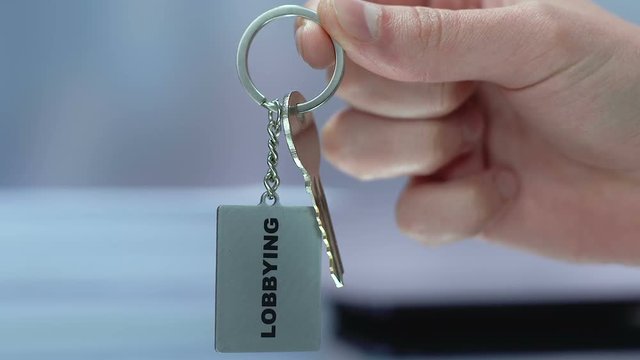 Politician holding lobbying keychain unfair promotion of initiatives in politics