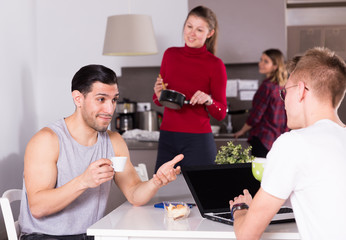 Man helping guy to plan tourist itinerary at hostel kitchen