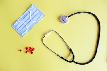 Medical stethoscope, stethoscope and red pills on a yellow background. Pills and treatments.