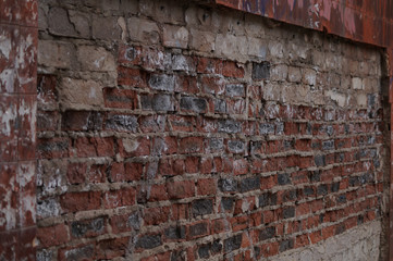 The wall is made of bricks of red, gray, black colors, having a pronounced texture.