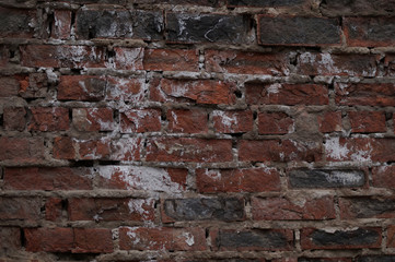 The wall is made of bricks of red, gray, black colors, having a pronounced texture.