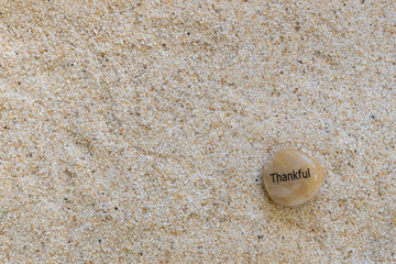 Close up sand background with a thankful rock and copy space