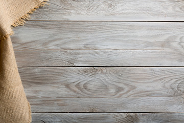 Burlap hessian sacking cloth on wooden table background with free space.