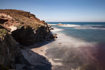Fototapeta na wymiar Rota dos pescadores, Costa Alentejana no sudoeste de Portugal, com as suas formações rochosas e águas transparentes, onde se pode ver a tonalidade avermelhada que as algas conferem á água.