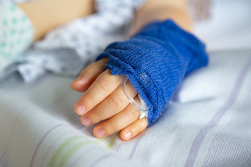 Sleeping sick child with peripheral venous line on his left hand in hospital - obrazy, fototapety, plakaty