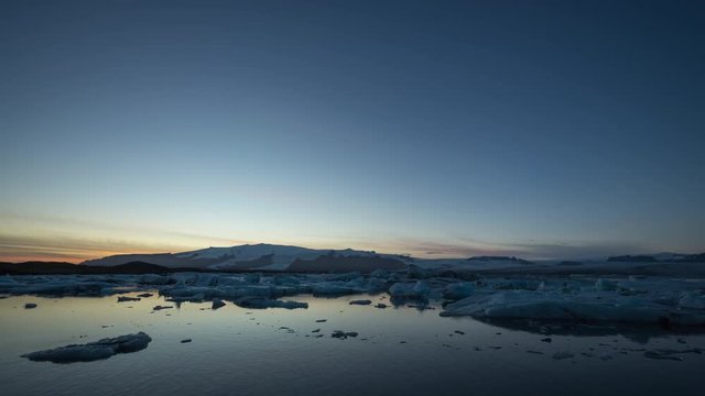 Timelapse of Glacier Lagoon / Jökulsarlón at sunrise with icebergs and clouds in view