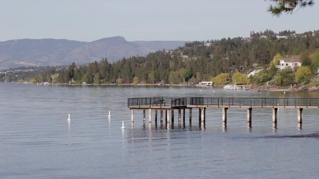 Wooden Pier Over Peaceful Lake Near Beach On Okanagan Lake On Calm Summer Day