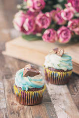 Handmade chocolate muffins with decorations. Book and a bouquet of roses