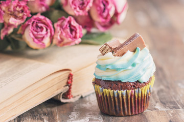 Handmade chocolate muffins with decorations. Book and a bouquet of roses