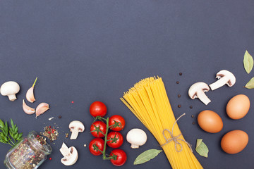 Top view of the ingredients for the preparation of Italian pasta. Pasta, eggs, tomatoes, mushrooms, garlic, spices, milk on a blue background with space for text. Flat lay