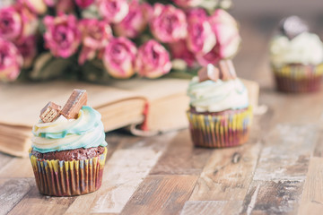 Handmade chocolate muffins with decorations. Book and a bouquet of roses