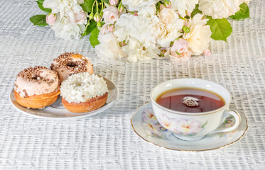 Still-life with a cup, cakes, a bouquet of roses, close-up