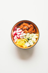 Hawaian trendy food of 2019 poke bowl, with radish tuna, salmon, jasmine rice, avocado, top view over a concrete gray backdrop, with mall bowl with ingredients, soya sauce, sesame, japanese hawaian ty