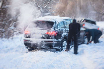 Process of taking out suv car stuck in snow, men digging and pushing the car out of snow, concept of winter problems with car