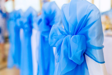 chairs are covered with white material with blue tulle and bow
