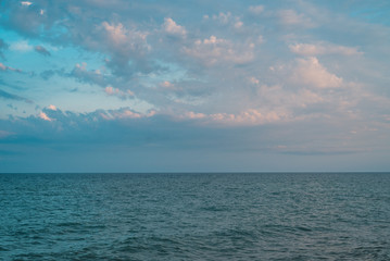 Sea view, ocean background. Clear calm sea with clouds on the sky.