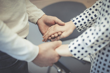 Obraz premium A man and a woman opposite each other hold hands. The concept of union, dialogue, confidential conversation between people.