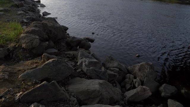 Still shot of the flowing of the trysil river in Norway with rocks during the sunset.