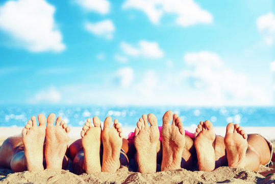 Group of friends having fun on the beach with their foots. Concept of summertime