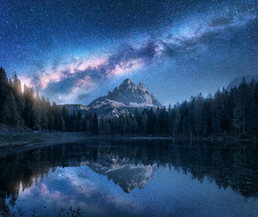 Milky Way over Antorno lake at night. Summer landscape with alpine mountains, trees, blue sky with...