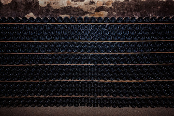 Bottles of red wine on a wooden shelf. Resting wine bottles stacked on wooden racks in cellar