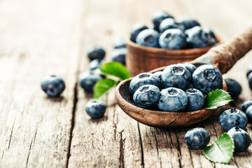 Blueberries in wooden spoon on old wood table. Healthy eating and nutrition concept.