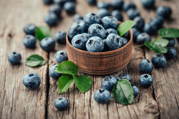 Freshly picked blueberries in wooden bowl on wooden background. Healthy eating and nutrition.