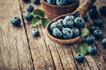 Blueberries in wooden spoon on old wood table. Healthy eating and nutrition concept.