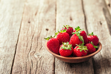 Freshly picked Strawberry in wooden bowl on wooden background. Healthy eating and nutrition.