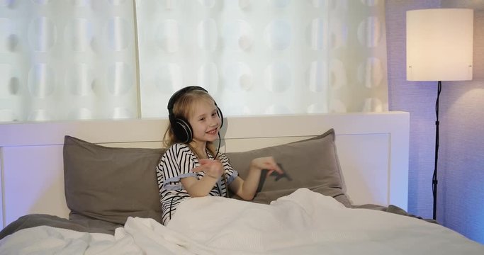 Sister and brother are listening to music with headphones in the bedroom.